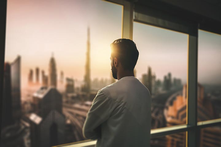 arabi business man looking at dubai city through glass window